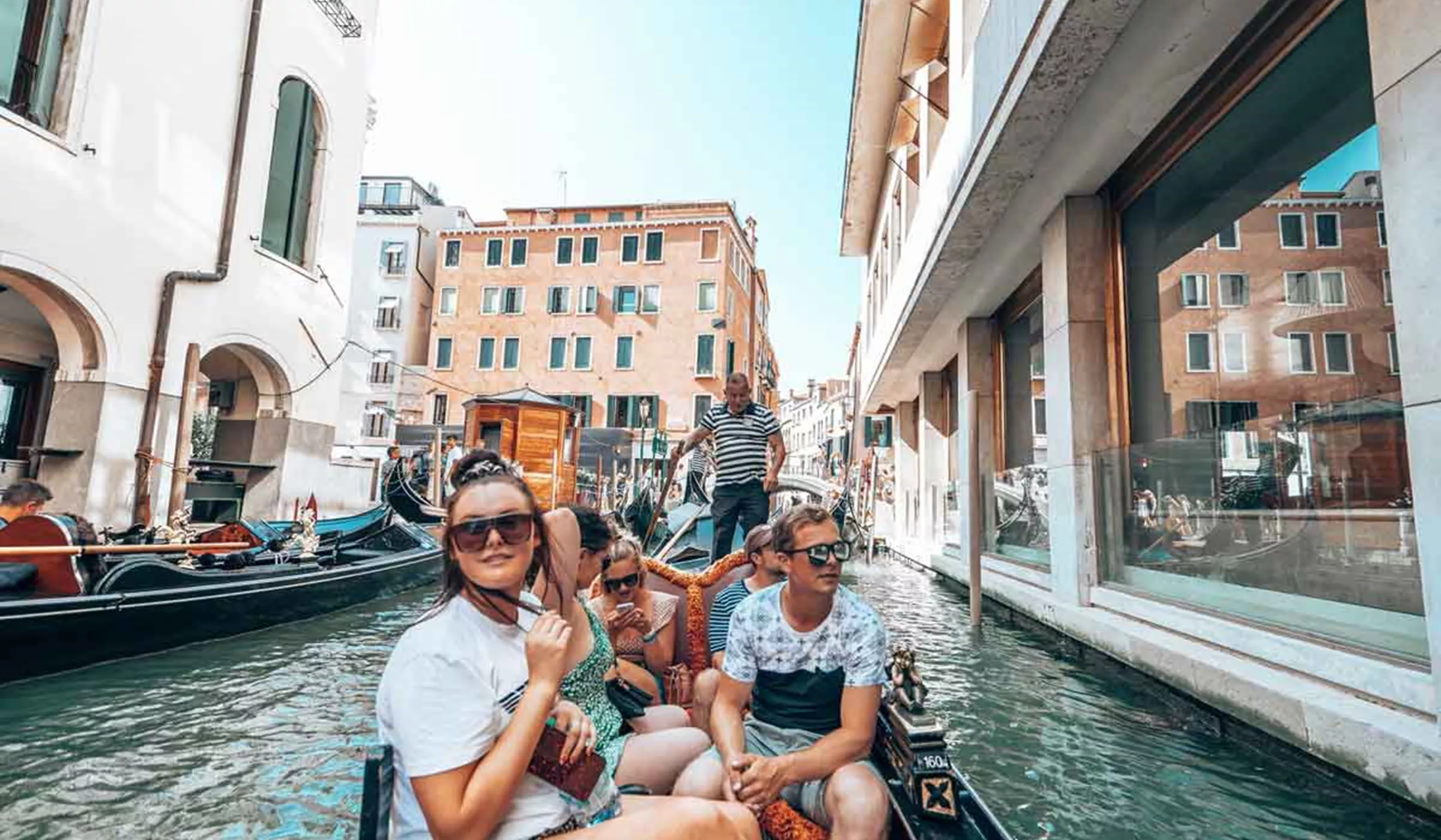 Group of happy friends in a boat in a canal in Venice, Italy