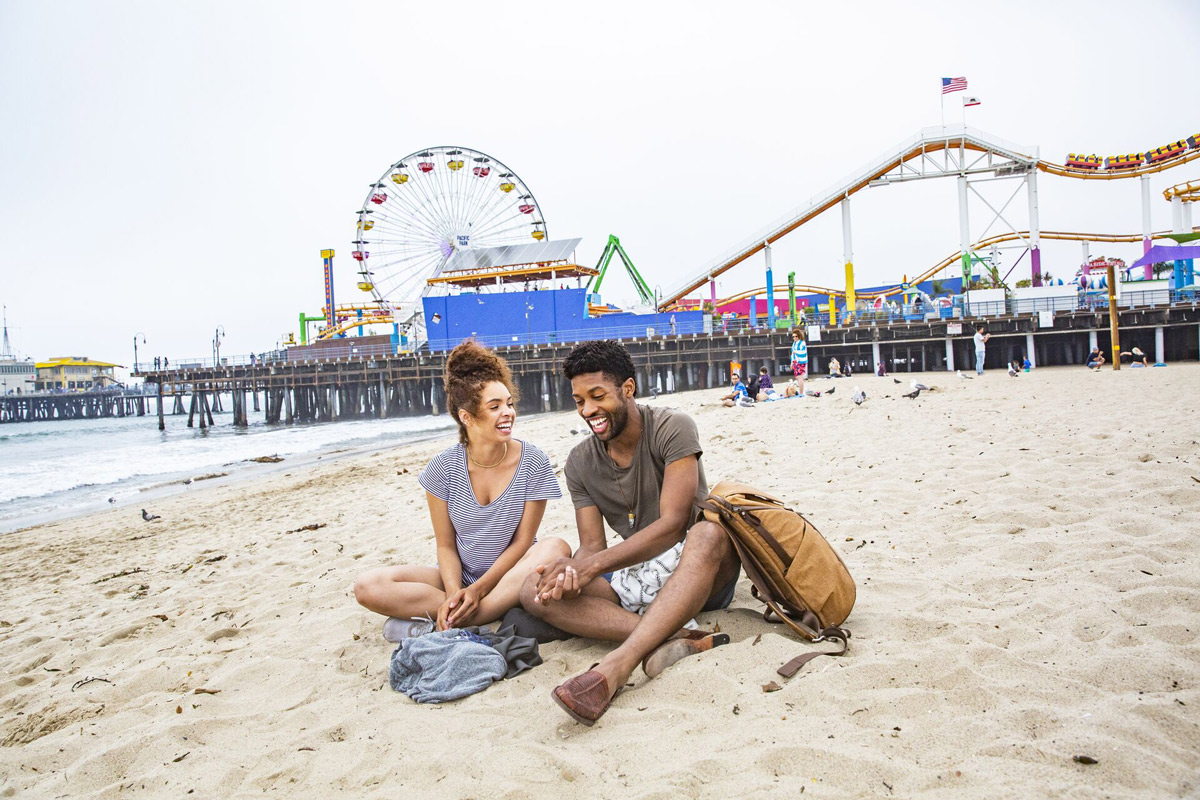Friends Sitting On The Beach Talking And Smiling in USA