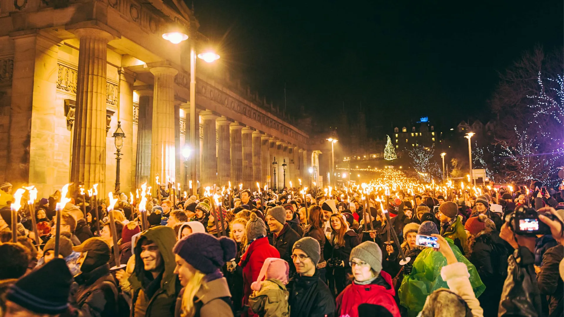 Contiki travellers joining the famous Edinburgh Hogmanay Torchlight Procession with thousands of torch-bearing revellers outside the Royal Scottish Academy at night