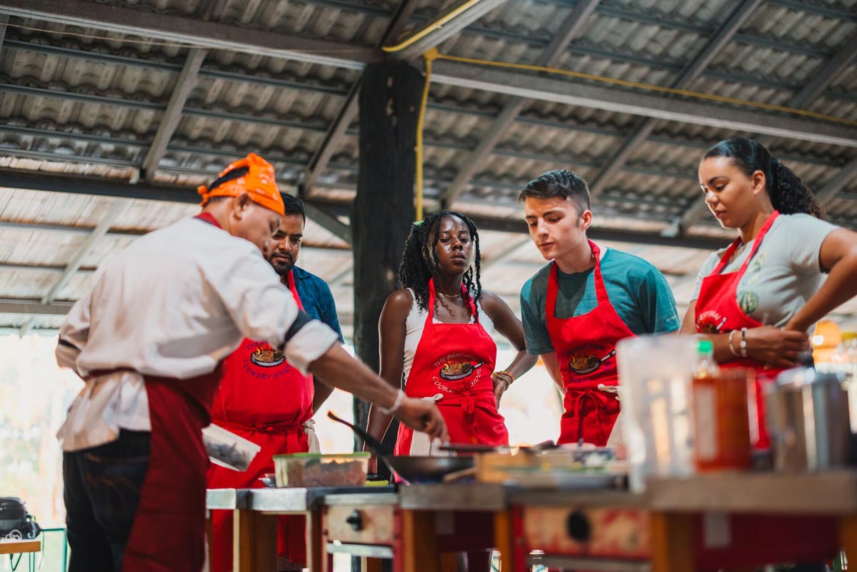 Group Of Young People Learning How To Cook From A Chef
