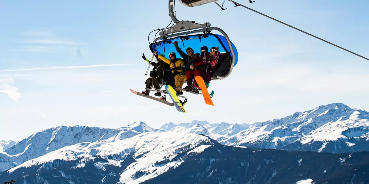 Travellers riding a chairlift with panoramic views of the Austrian Alps on the Contiki Ski Austria 35 to 45 Tour