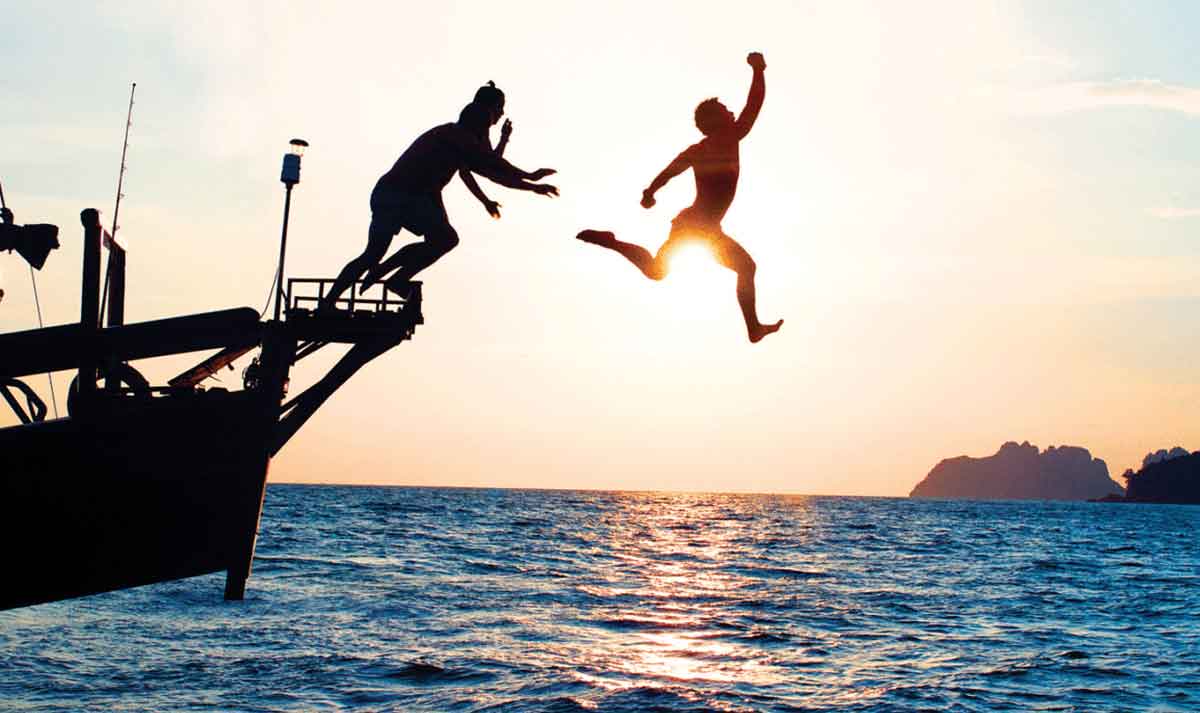 Sunset And People Jumping From Boat To Sea