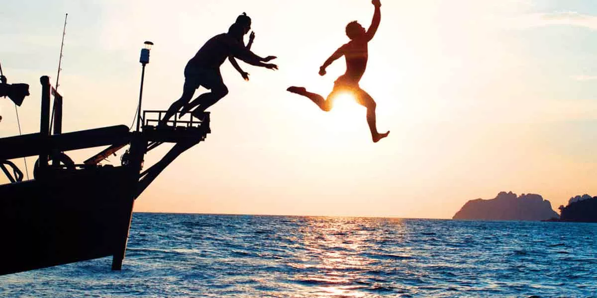 Sunset And People Jumping From Boat To Sea