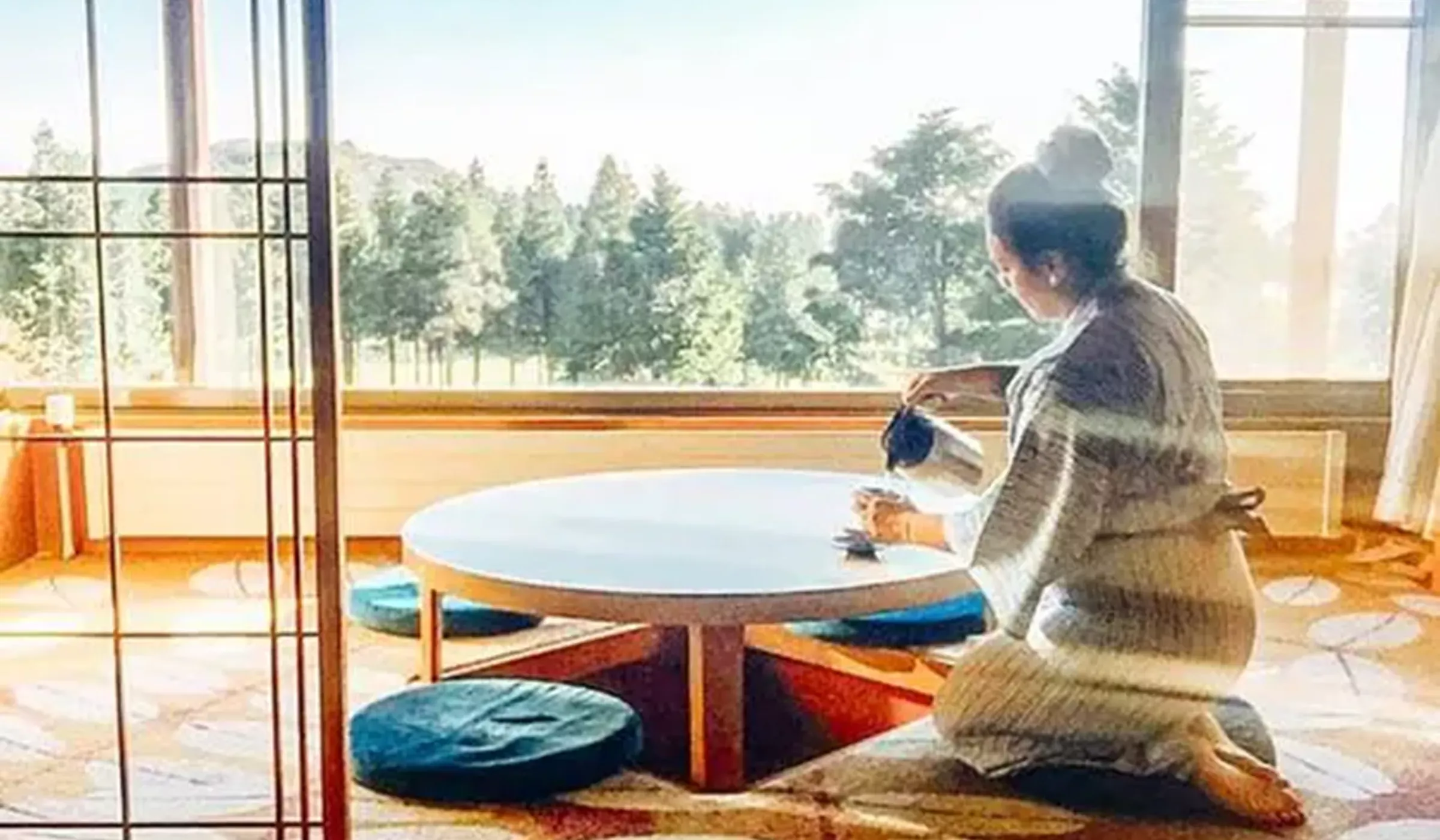 Woman in traditional dress pouring tea at a low table beside large windows overlooking forest, Buddhist guest house, Mount Koya, Japan