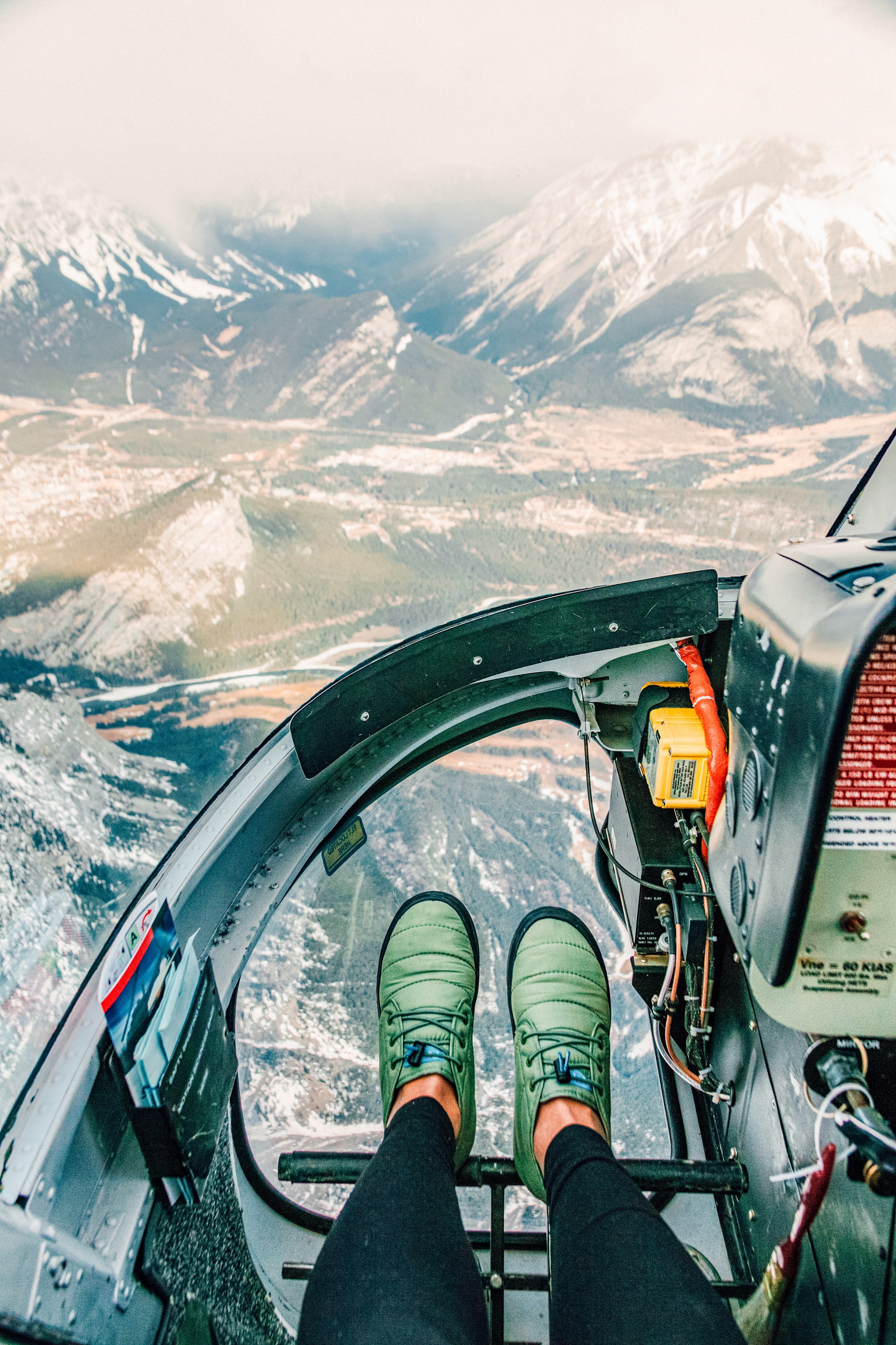 Travellers feet in a helicopter over Mt Assiniboine in Banff, Canada