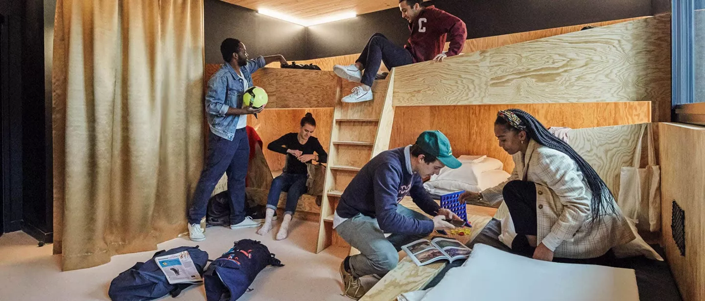 A group of people sitting on wooden bunk beds