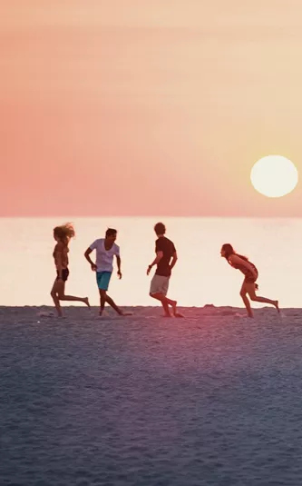 Sunset over Miami Beach with the iconic Art Deco lifeguard tower and travellers enjoying the shoreline on the Contiki Dallas to Miami Tour