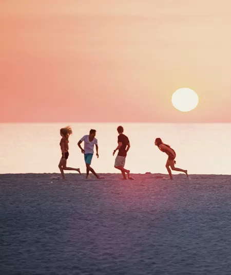 Sunset over Miami Beach with the iconic Art Deco lifeguard tower and travellers enjoying the shoreline on the Contiki Dallas to Miami Tour
