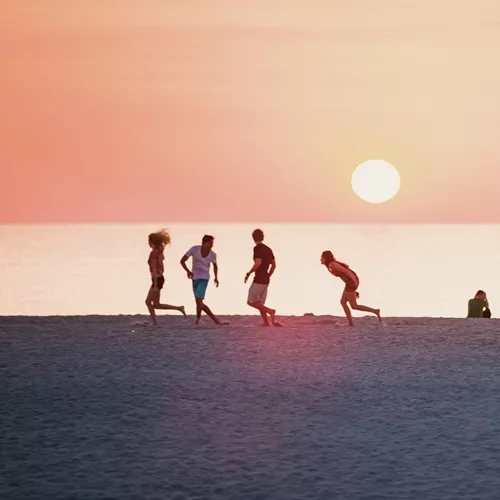 Sunset over Miami Beach with the iconic Art Deco lifeguard tower and travellers enjoying the shoreline on the Contiki Dallas to Miami Tour