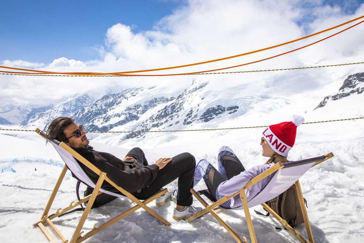 Friends Sittign And Relaxing While Looking At Snowy Mountain