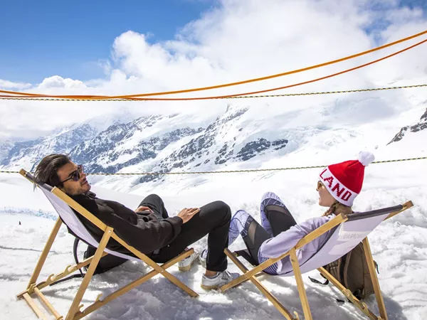 Friends Sittign And Relaxing While Looking At Snowy Mountain