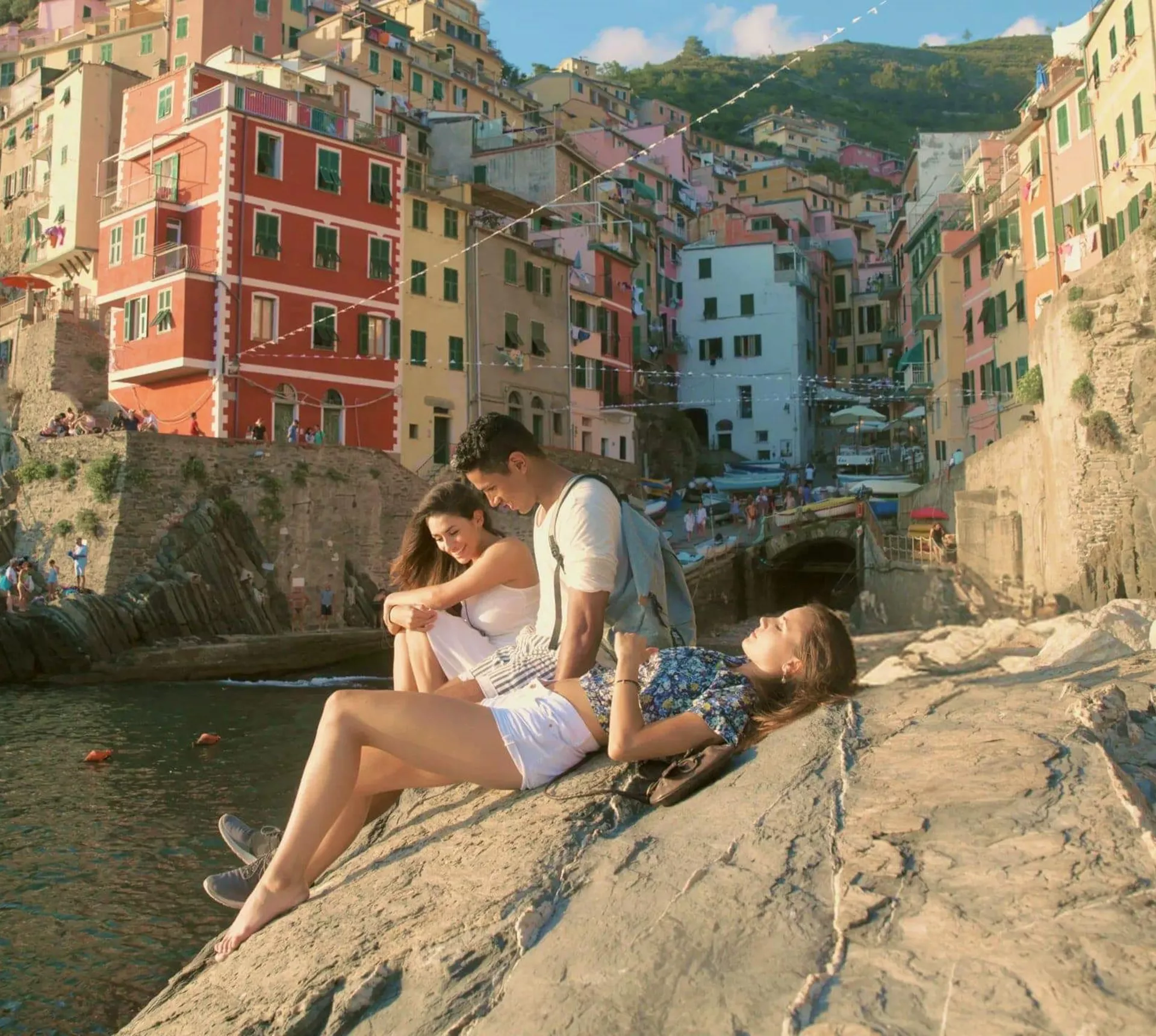 Three people relaxing by the sea in Riomaggiore, Cinque Terre - Contiki Tuscany, Milan & Venice Tour