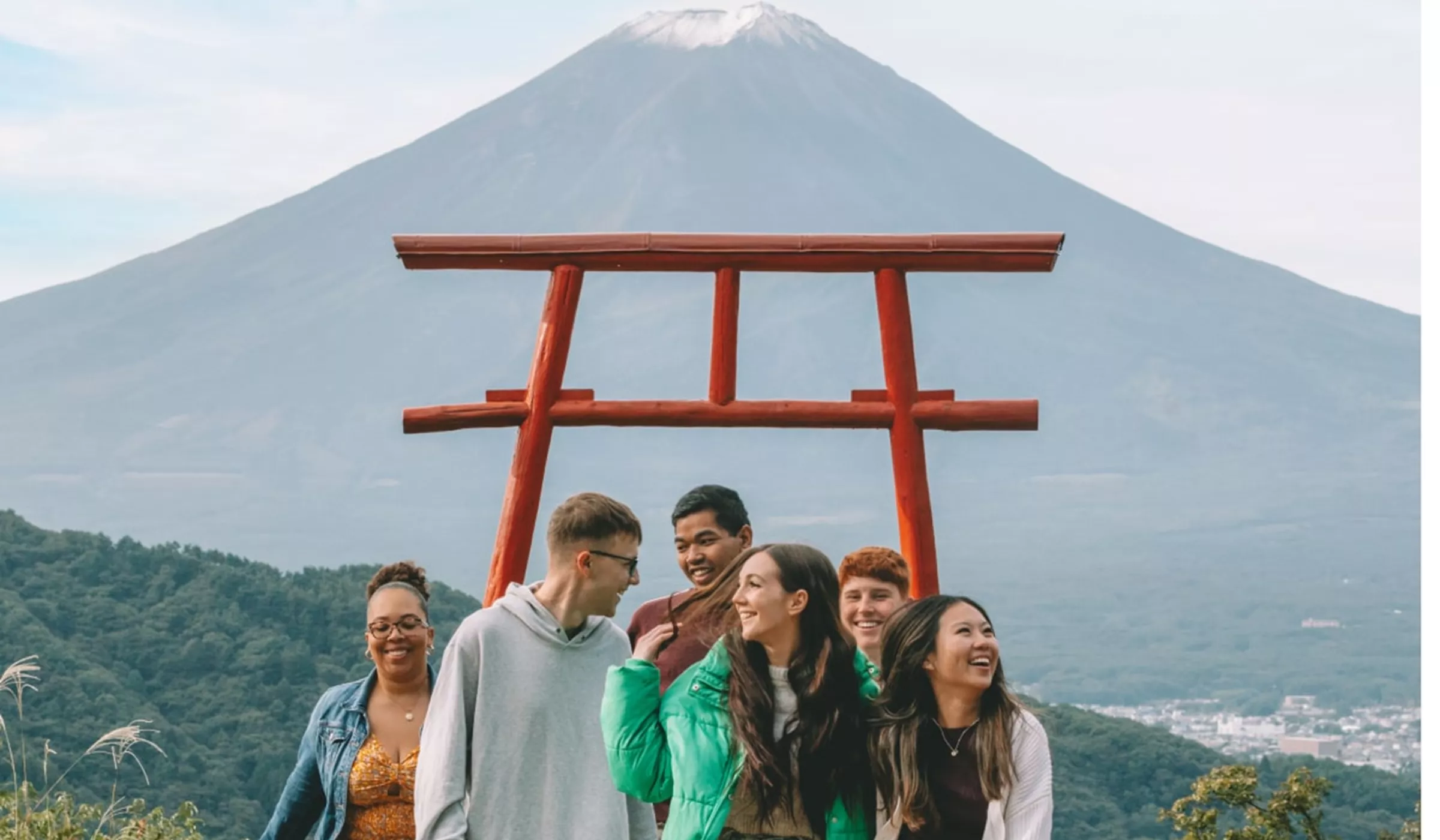 People standing in front of a wooden structure with Mount Fuji in the background