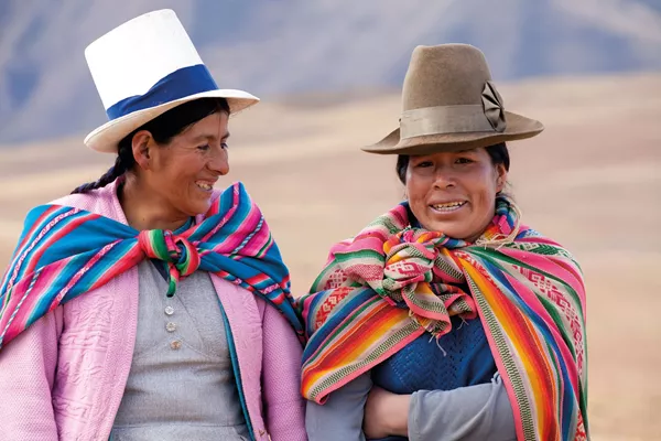 Two Women In Traditional Costume Walking In The Mountains Near Moray Peru