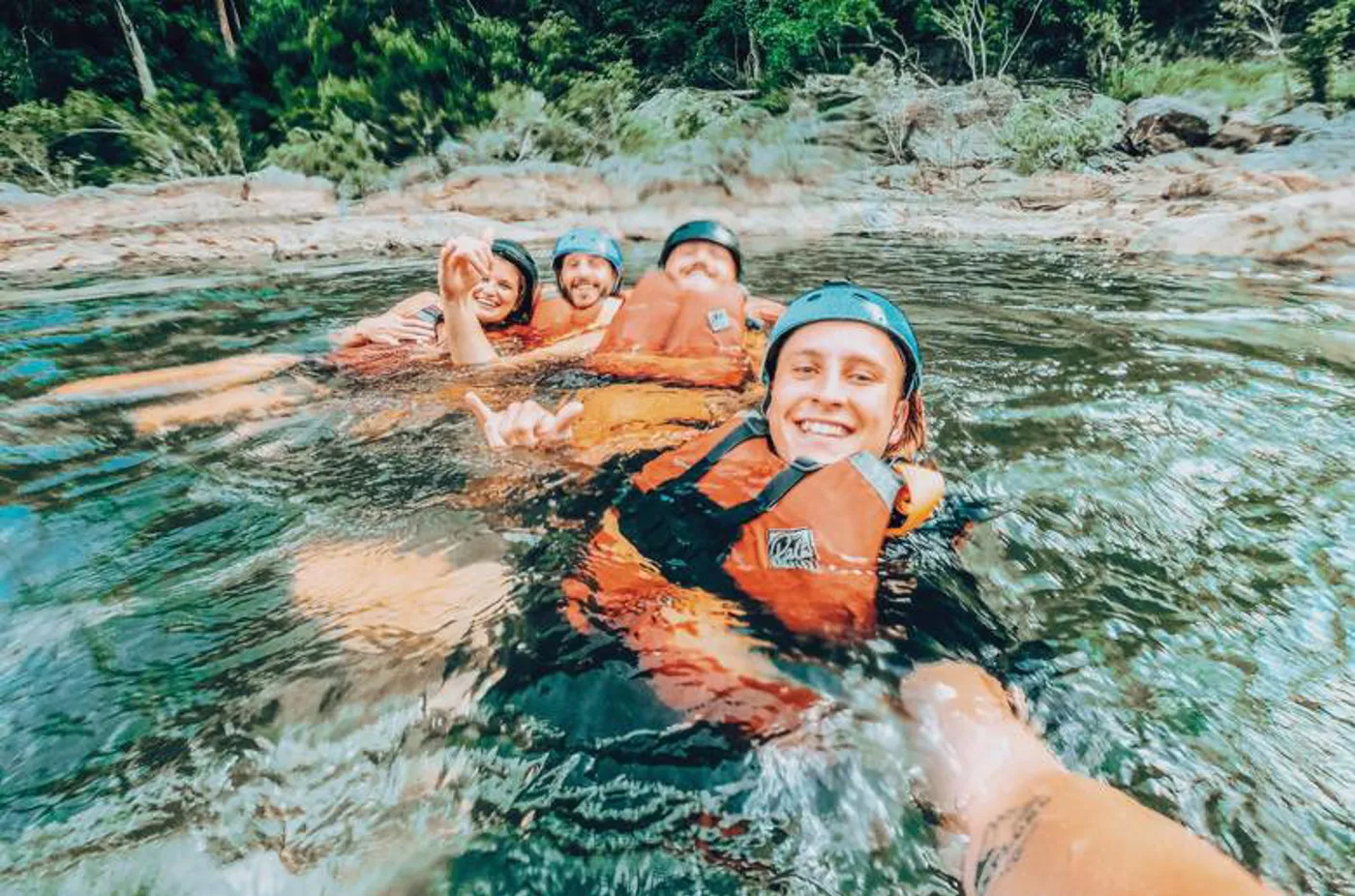 Group enjoying a water adventure in helmets and life vests.