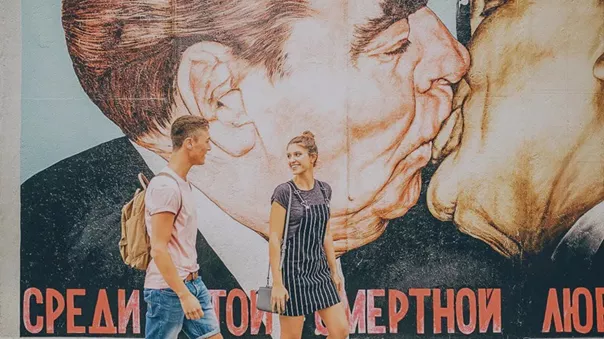 Smiling couple and mural with kissing men