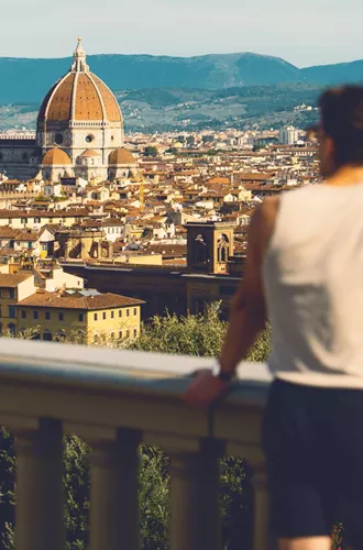 Traveller at Piazzale Michelangelo overlooking the Florence skyline with Brunelleschi's Duomo and Campanile in Tuscany Italy - Contiki European Discovery Tour