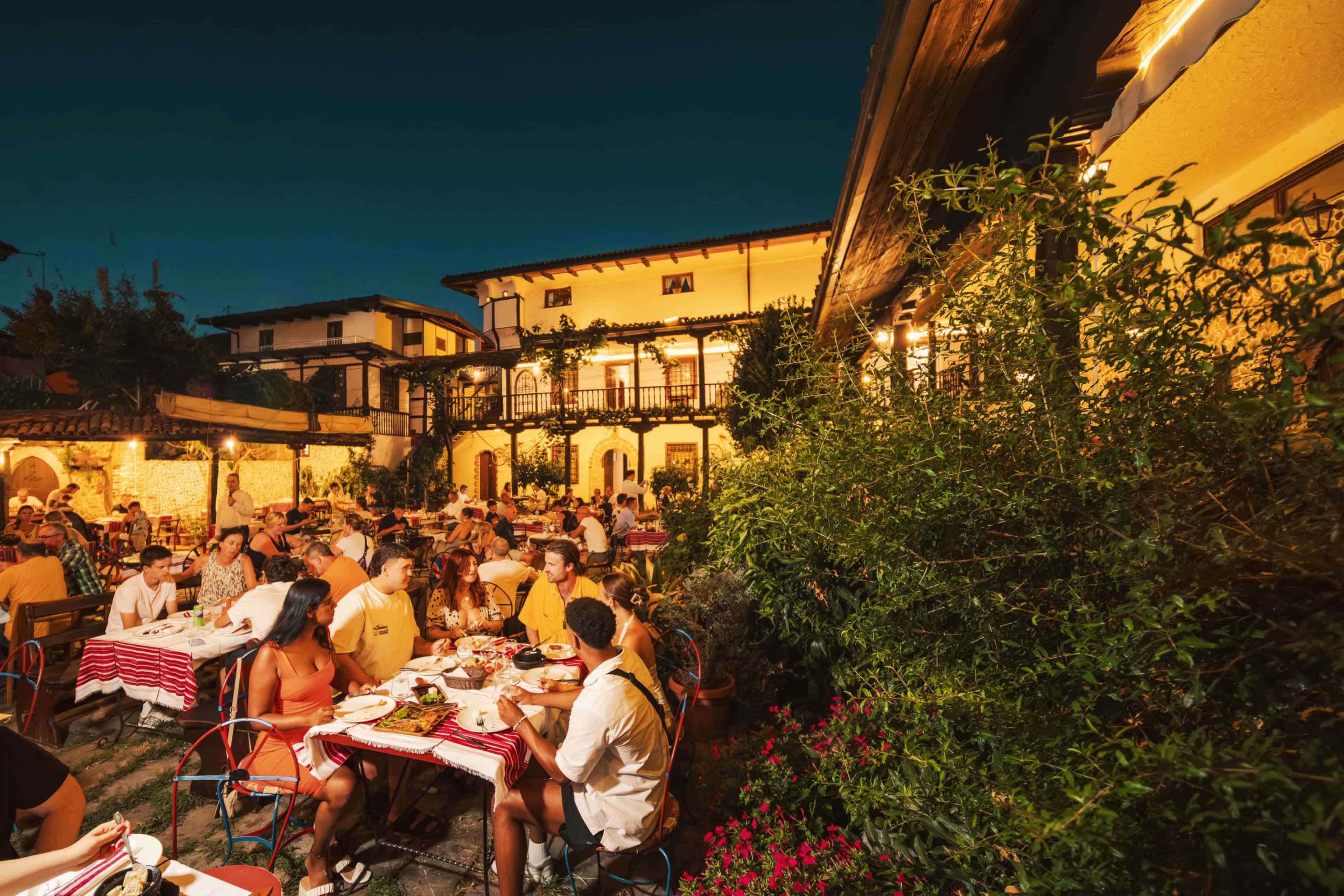 Travellers dining together at a lantern-lit outdoor restaurant in Berat, Albania