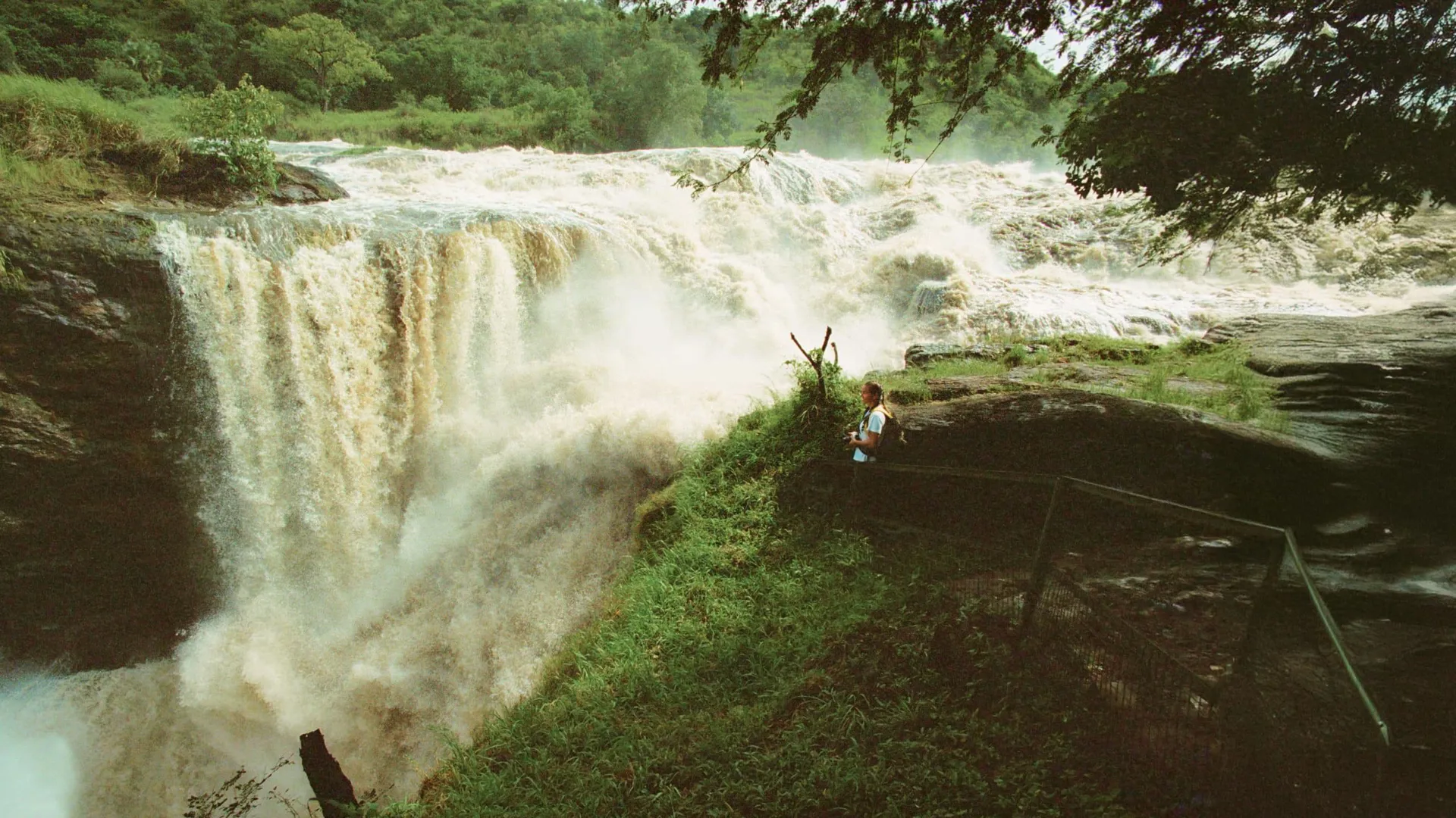 Traveller standing at the viewing platform beside the thundering Murchison Falls on the Victoria Nile in Murchison Falls National Park Uganda - Contiki Uganda Tour
