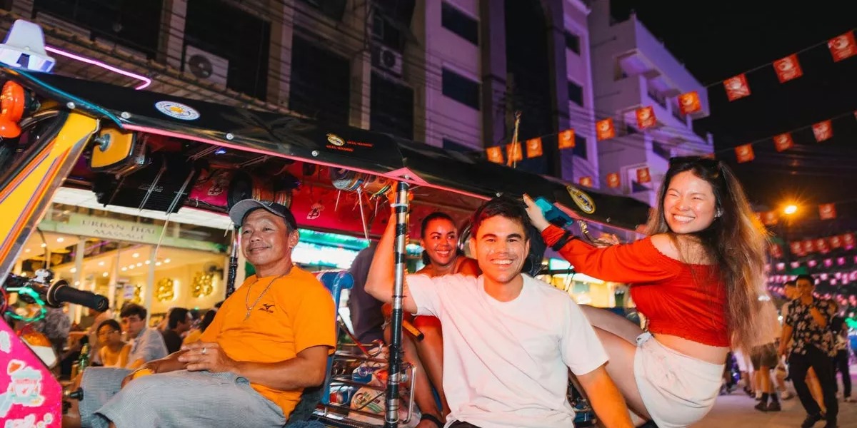 Friends enjoying a ride in a tuk-tuk at night in Thailand.