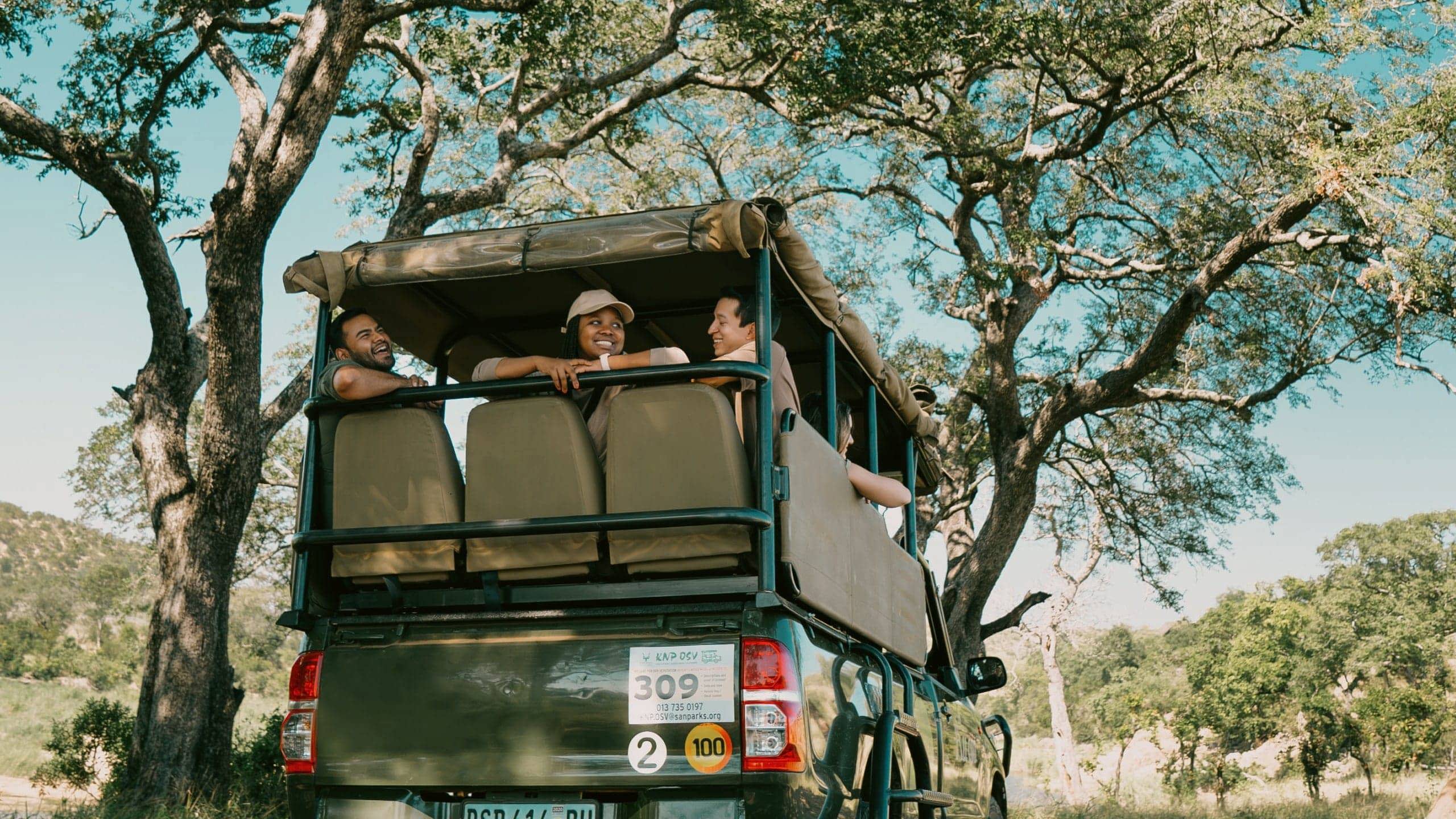 Travellers riding in an open safari vehicle during a game drive - Contiki South Africa & Botswana Safari Tour