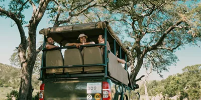 Travellers riding in an open safari vehicle during a game drive - Contiki South Africa & Botswana Safari Tour