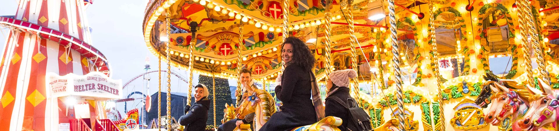 Group Enjoying Carousel At Christmas Fair In London 0143EURW2018