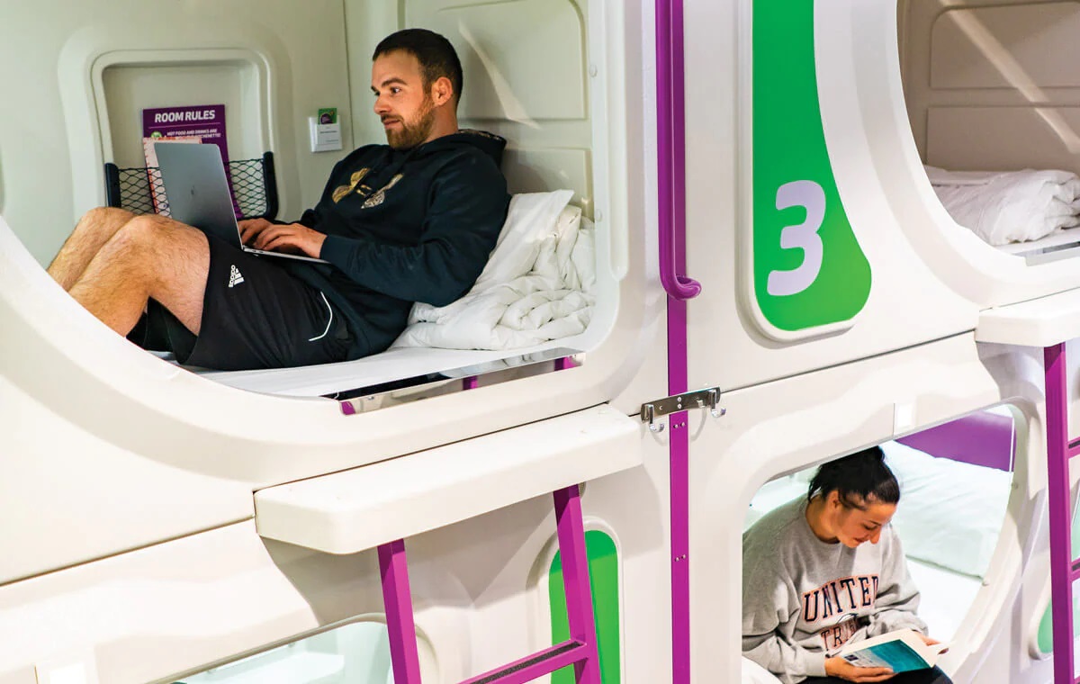 A man and a woman sitting on their beds 