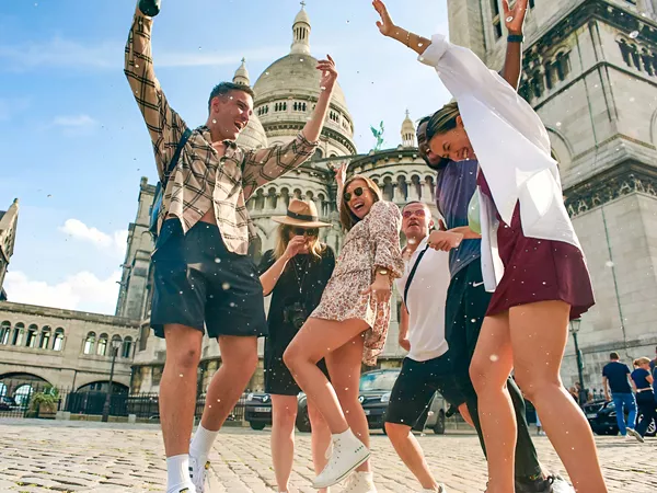 People Happily Jumping Sunny Day Landmark As Background
