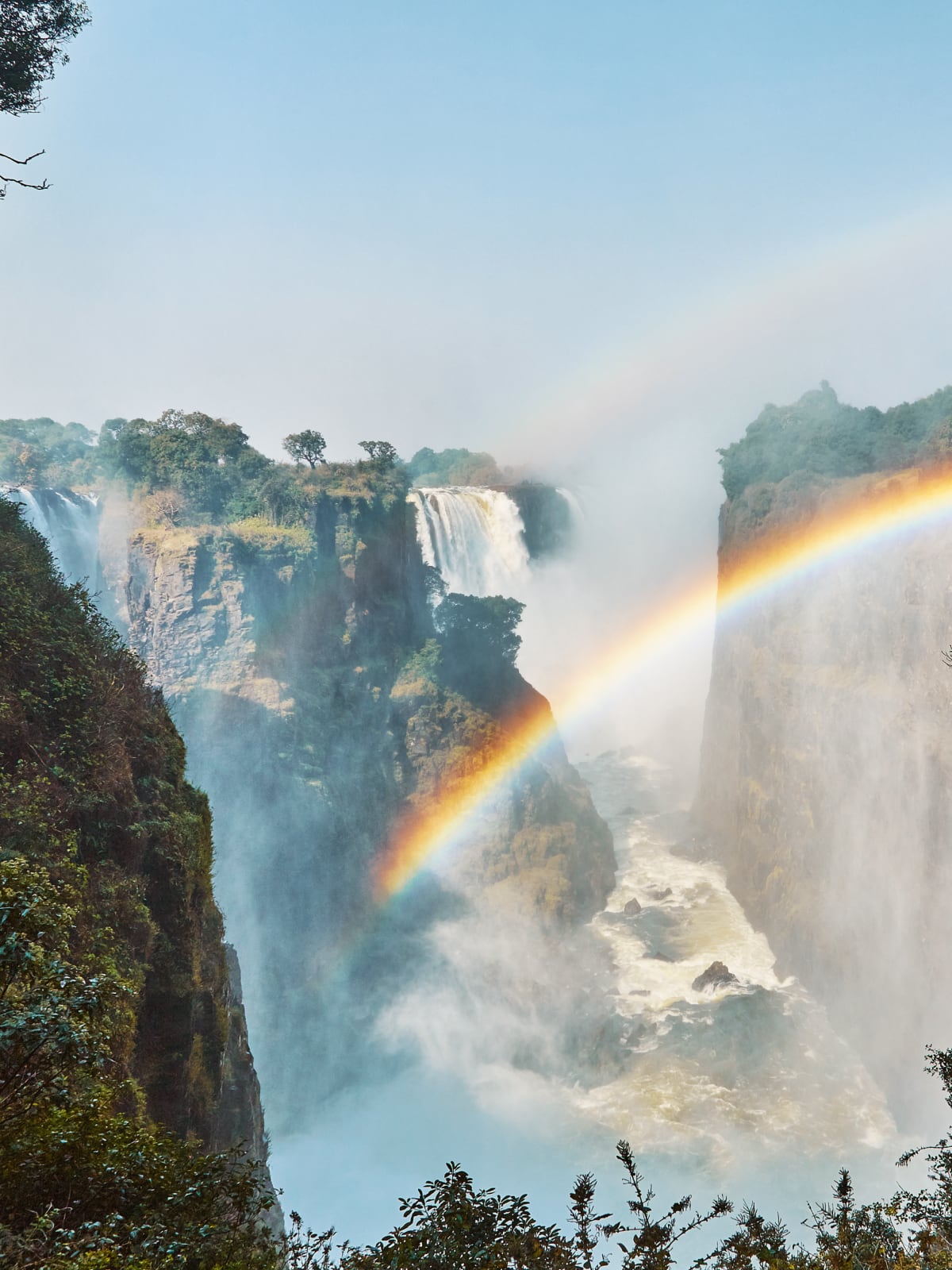 Rainbow arching over the misting cascades of Victoria Falls, Zimbabwe