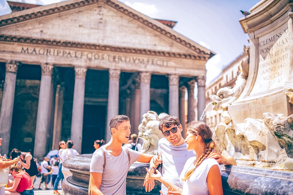 Three Friends Talking Close To A Monument Sunny Day in Austria.
