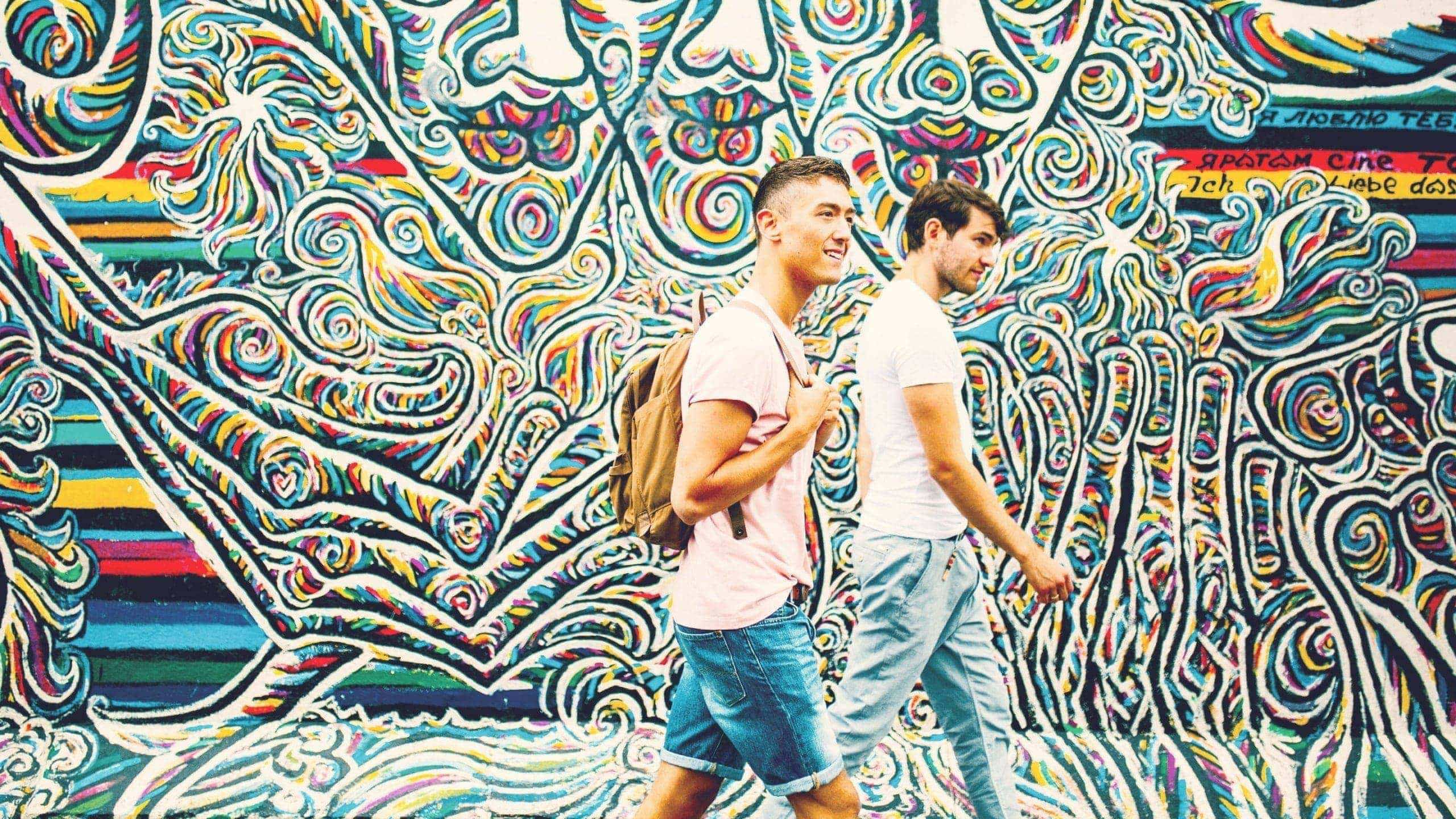 Contiki travellers walking past the colourful East Side Gallery murals in Berlin on the Rome to London Quest Tour