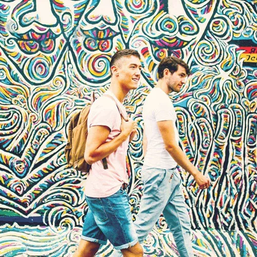 Contiki travellers walking past the colourful East Side Gallery murals in Berlin on the Rome to London Quest Tour