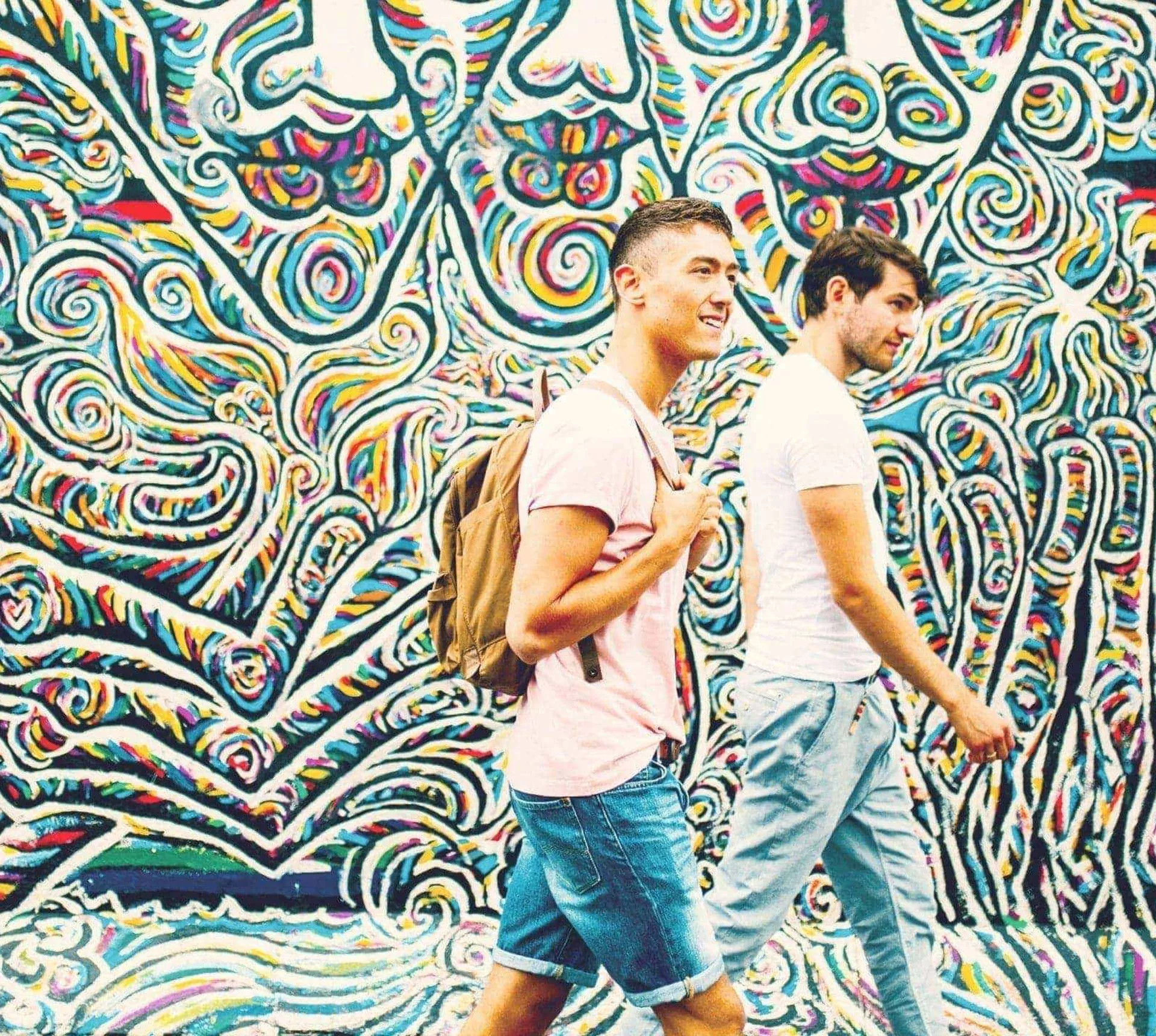 Contiki travellers walking past the colourful East Side Gallery murals in Berlin on the Rome to London Quest Tour