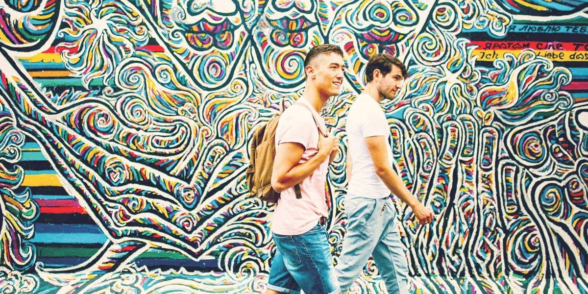 Contiki travellers walking past the colourful East Side Gallery murals in Berlin on the Rome to London Quest Tour