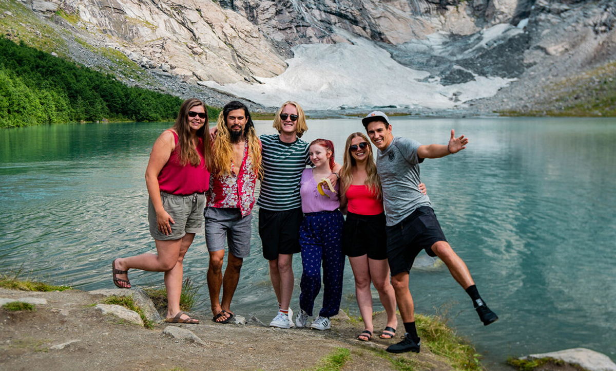 Group Of Travellers In Front Of Mountain In Scandi