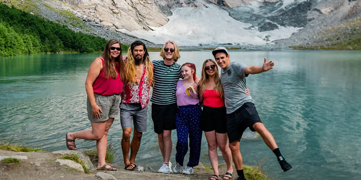 Group Of Travellers In Front Of Mountain In Scandi