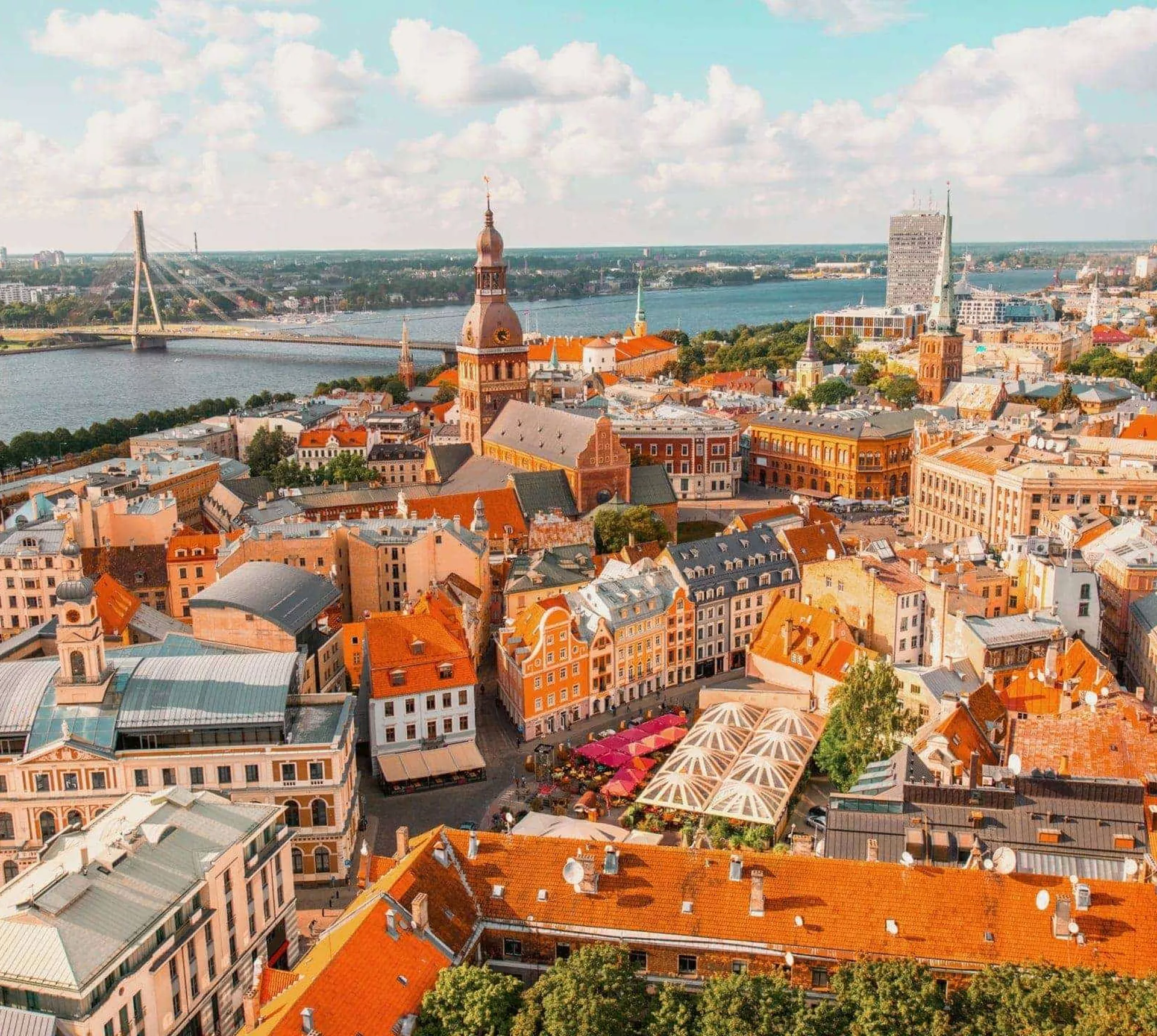 An aerial view of Riga's historic centre, with church spires, colourful rooftops and the Daugava River stretching across the city