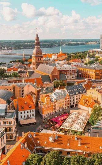 An aerial view of Riga's historic centre, with church spires, colourful rooftops and the Daugava River stretching across the city