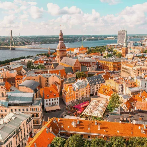 An aerial view of Riga's historic centre, with church spires, colourful rooftops and the Daugava River stretching across the city