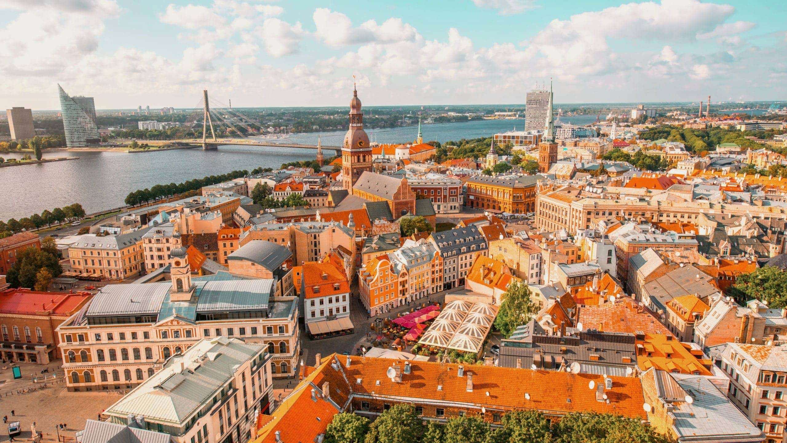 An aerial view of Riga's historic centre, with church spires, colourful rooftops and the Daugava River stretching across the city