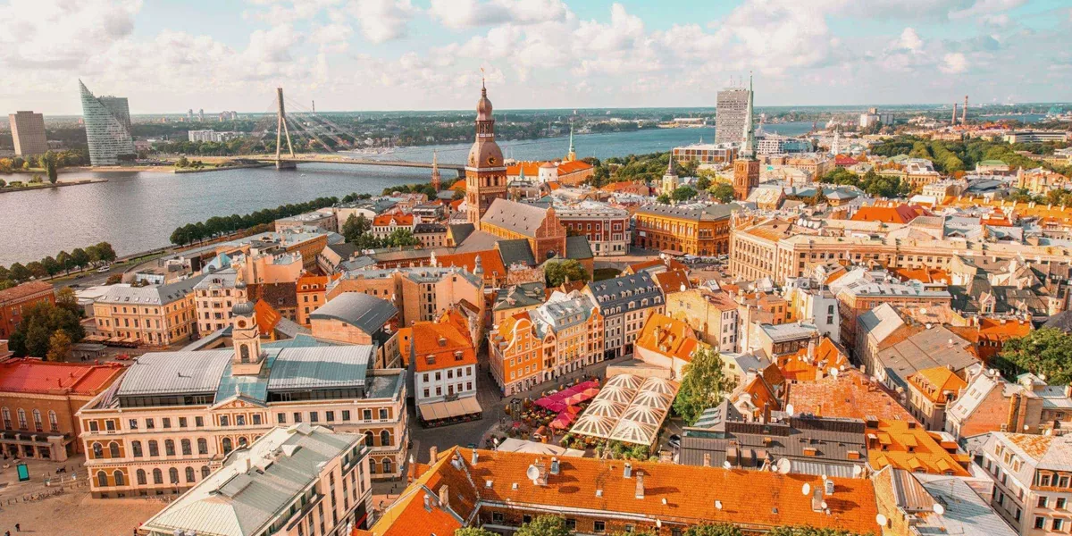 An aerial view of Riga's historic centre, with church spires, colourful rooftops and the Daugava River stretching across the city