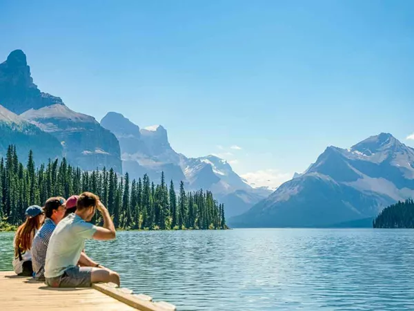Trio Of Travelers Sitting Near Lake In Canada