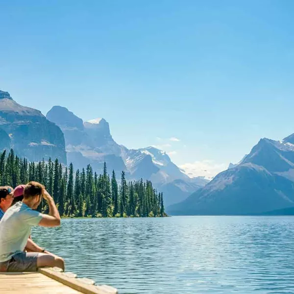 Trio Of Travelers Sitting Near Lake In Canada