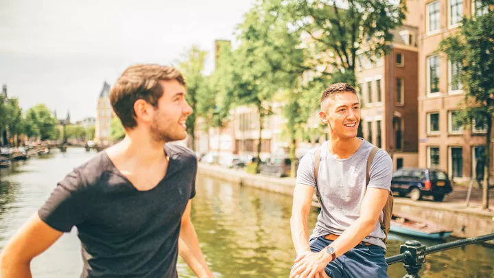 Travellers on a canal bridge in Amsterdam, Netherlands