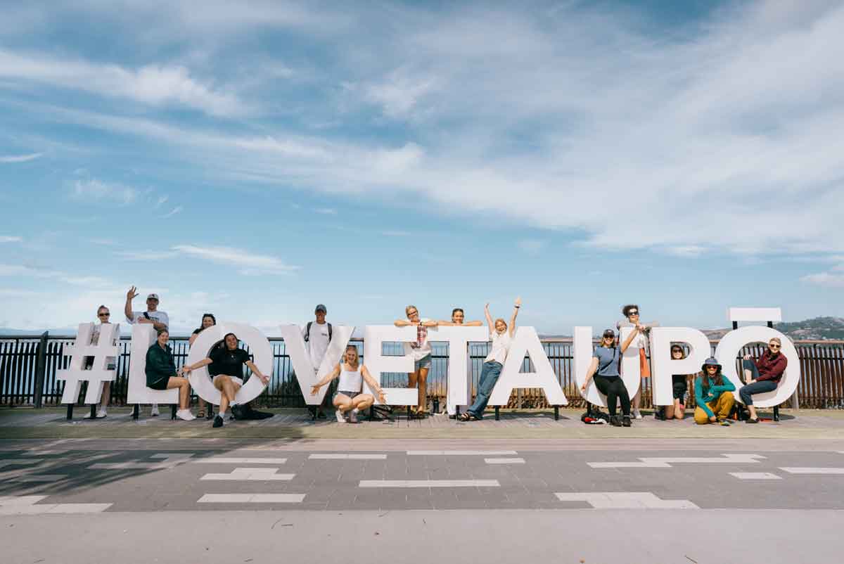 Travellers Standing By Lake Taupo In New Zealand