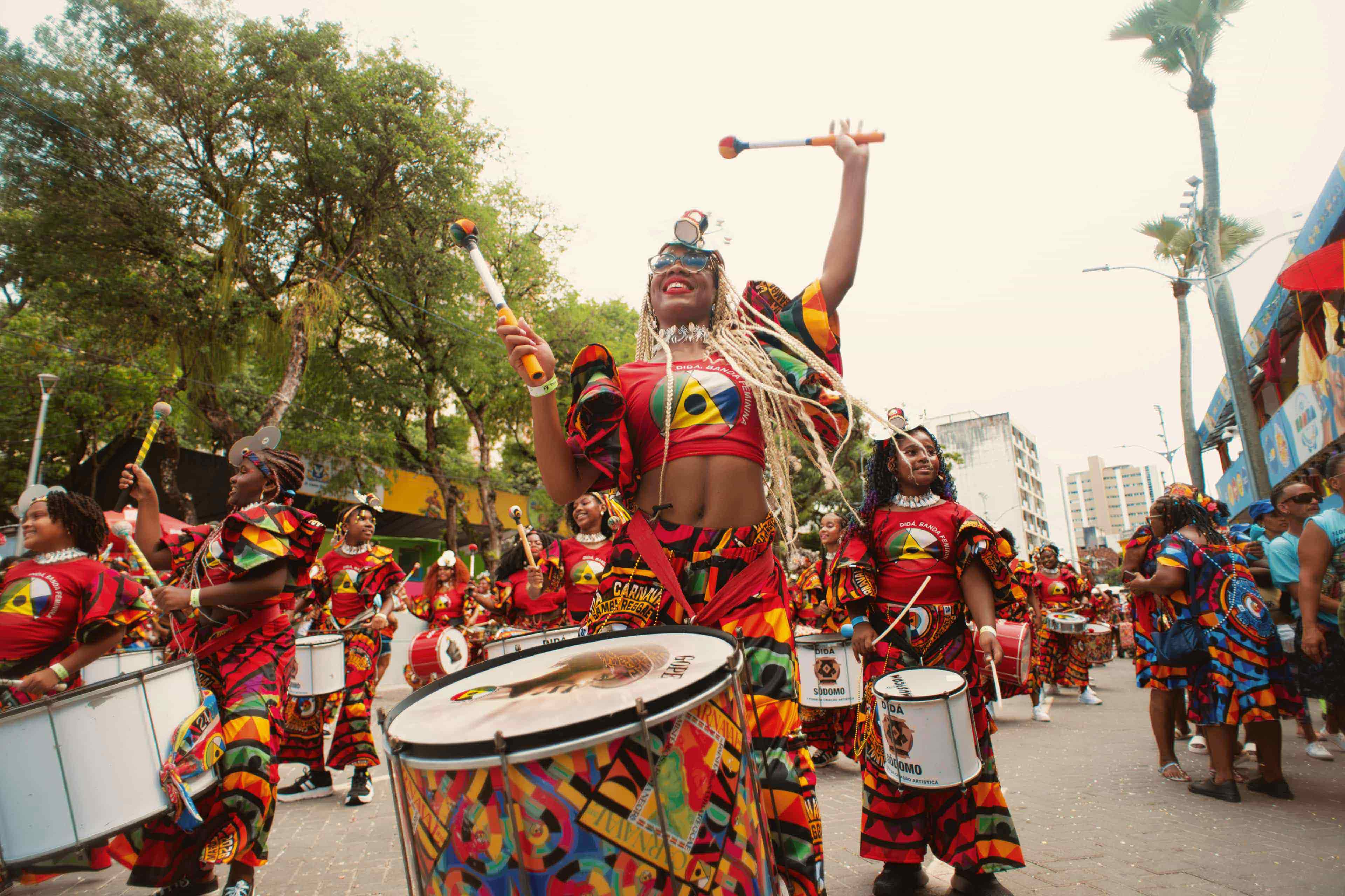 Drummers in vibrant costume performing at a street carnival in Brazil.