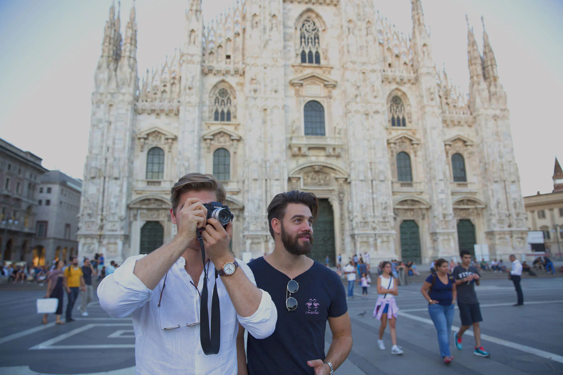Two men standing next to a building with a camera