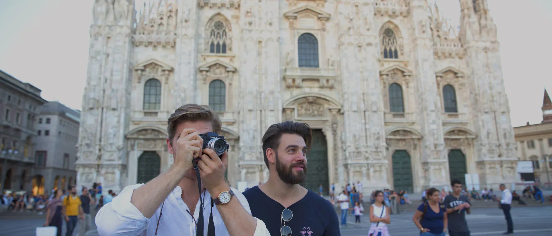 Two men standing next to a building with a camera