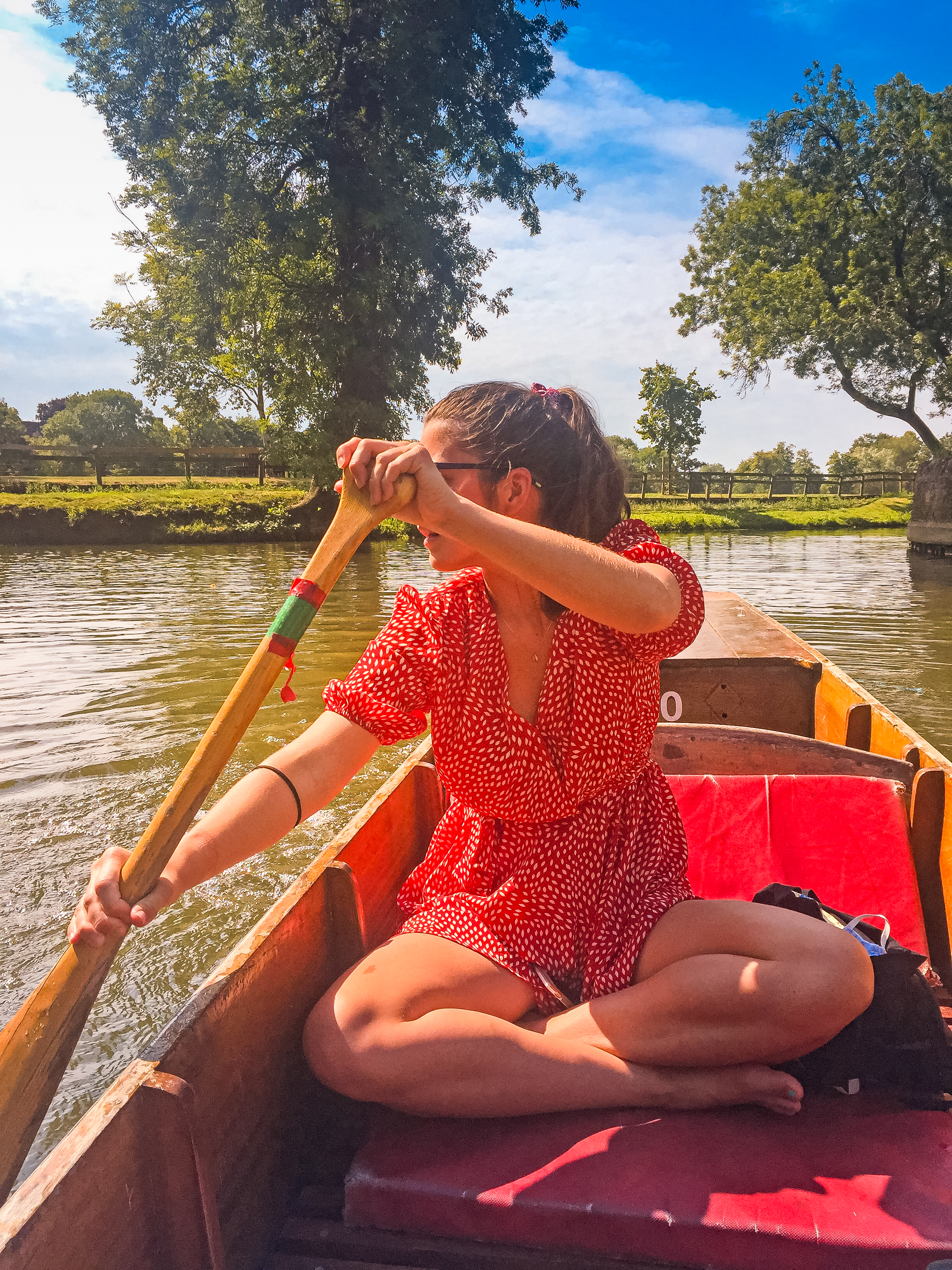 Traveller sitting in a punt boat steering along the river in Oxford, United Kingdom